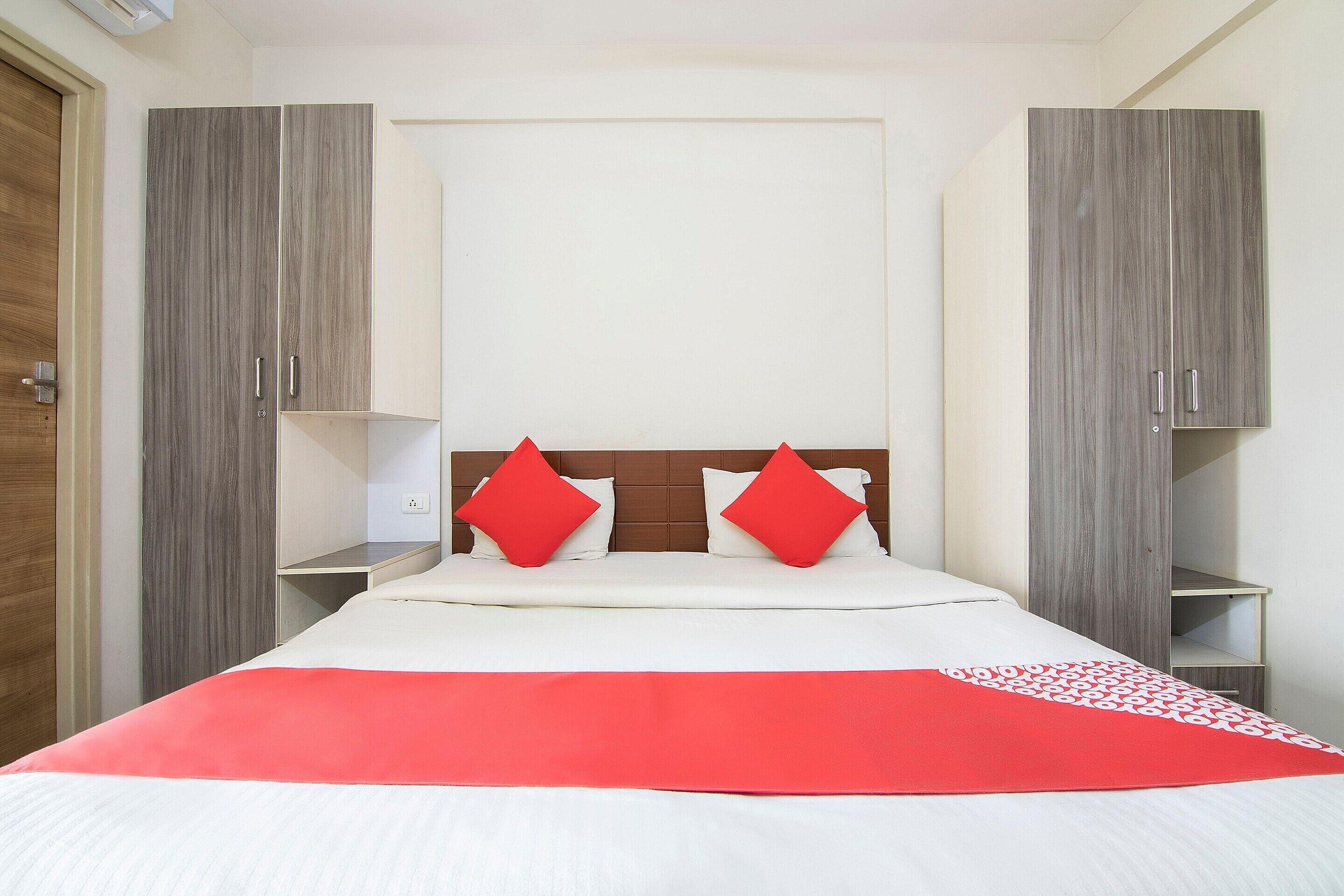 Une chambre à coucher comprenant un lit, deux tables de chevet, une armoire et une porte.