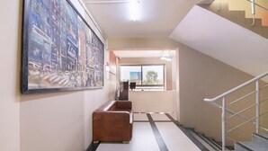 A hallway with a large painting, a sofa, and a staircase.
