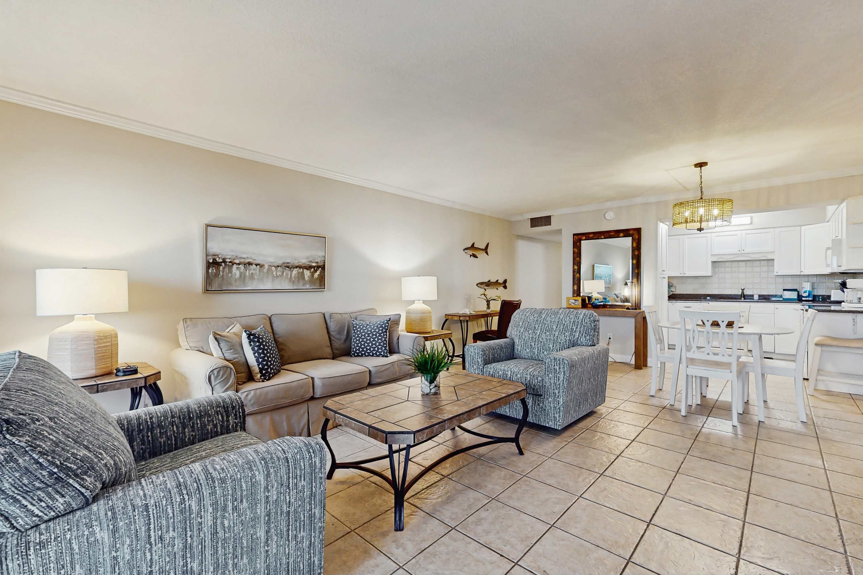 Uma sala de estar moderna com sofá, poltronas, mesa de centro e área de jantar com mesa e cadeiras.