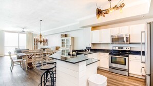 Una cocina moderna con armarios blancos, electrodomésticos de acero inoxidable y una isla central.
