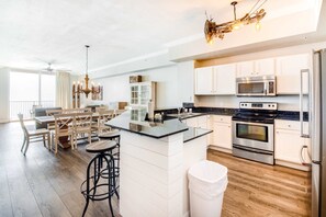 A modern kitchen with white cabinetry, stainless steel appliances, and a central island. - 29th-floor, oceanfront condo with pool, ocean view & high-speed WiFi (Panama City Beach)