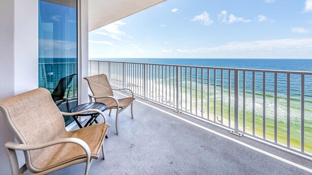 A balcony with two chairs and a table, overlooking a beach with the ocean and a clear sky. - Inviting Gulf-front condo In Perdido Key with waterfront pool/hot tub,oceanfront balcony & private cabana (Perdido Key)