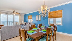 A dining area with a table set for six, a chandelier, and a view of the ocean through large windows. - Inviting Gulf-front condo In Perdido Key with waterfront pool/hot tub,oceanfront balcony & private cabana (Perdido Key)