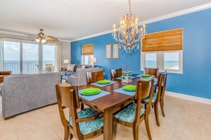 A dining area with a table set for six, a chandelier, and a view of the ocean through large windows. - Inviting Gulf-front condo In Perdido Key with waterfront pool/hot tub,oceanfront balcony & private cabana (Perdido Key)