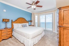 A bedroom with a large bed, wooden headboard, two bedside tables with lamps, a ceiling fan, and a view of the ocean through large windows. - Inviting Gulf-front condo In Perdido Key with waterfront pool/hot tub,oceanfront balcony & private cabana (Perdido Key)
