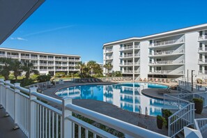 Ein Hotel mit Pool, mehreren Balkonen und blauem Himmel.