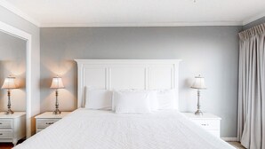 Ein ordentlich eingerichtetes Schlafzimmer mit einem großen Bett, zwei Nachttischen mit Lampen und einem Kopfteil.