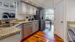 Eine moderne Küche mit Granit-Arbeitsplatten, Edelstahlgeräten und Holzboden.