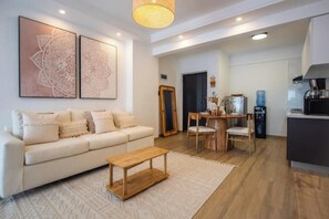 En moderne stue med sofa, sofabord og et kunstværk på væggen.