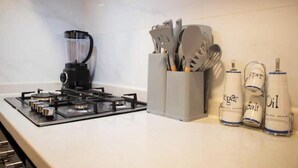 Une cuisine équipée d’une cuisinière à gaz, d’un mixeur et d’un porte-ustensiles.