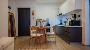 Un espace de vie compact comprenant un coin repas, une kitchenette et une porte donnant sur une autre pièce.