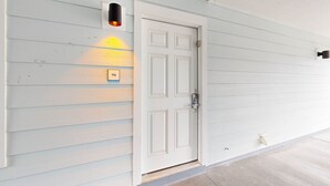 A white door with a keypad lock, a mailbox, and a wall-mounted light fixture. - Beachside Villas | 1st Floor Condo | 6-min Walk to Beach | Pools (Santa Rosa Beach)