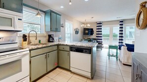 A kitchen with a microwave, stove, sink, and dishwasher. There is a dining area with a table and chairs. - Beachside Villas | 1st Floor Condo | 6-min Walk to Beach | Pools (Santa Rosa Beach)