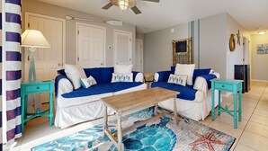 A room with two blue and white sofas, a wooden coffee table, teal side tables, a ceiling fan, and a starfish rug. - Beachside Villas | 1st Floor Condo | 6-min Walk to Beach | Pools (Santa Rosa Beach)