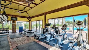 A gym with treadmills, elliptical machines, and free weights, large windows, and a ceiling fan. - Gorgeous, private, coastal home with a shared pool, fitness room (Santa Rosa Beach)