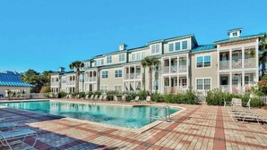 A hotel with a swimming pool, multiple balconies, and a brick patio area. - Gorgeous, private, coastal home with a shared pool, fitness room (Santa Rosa Beach)