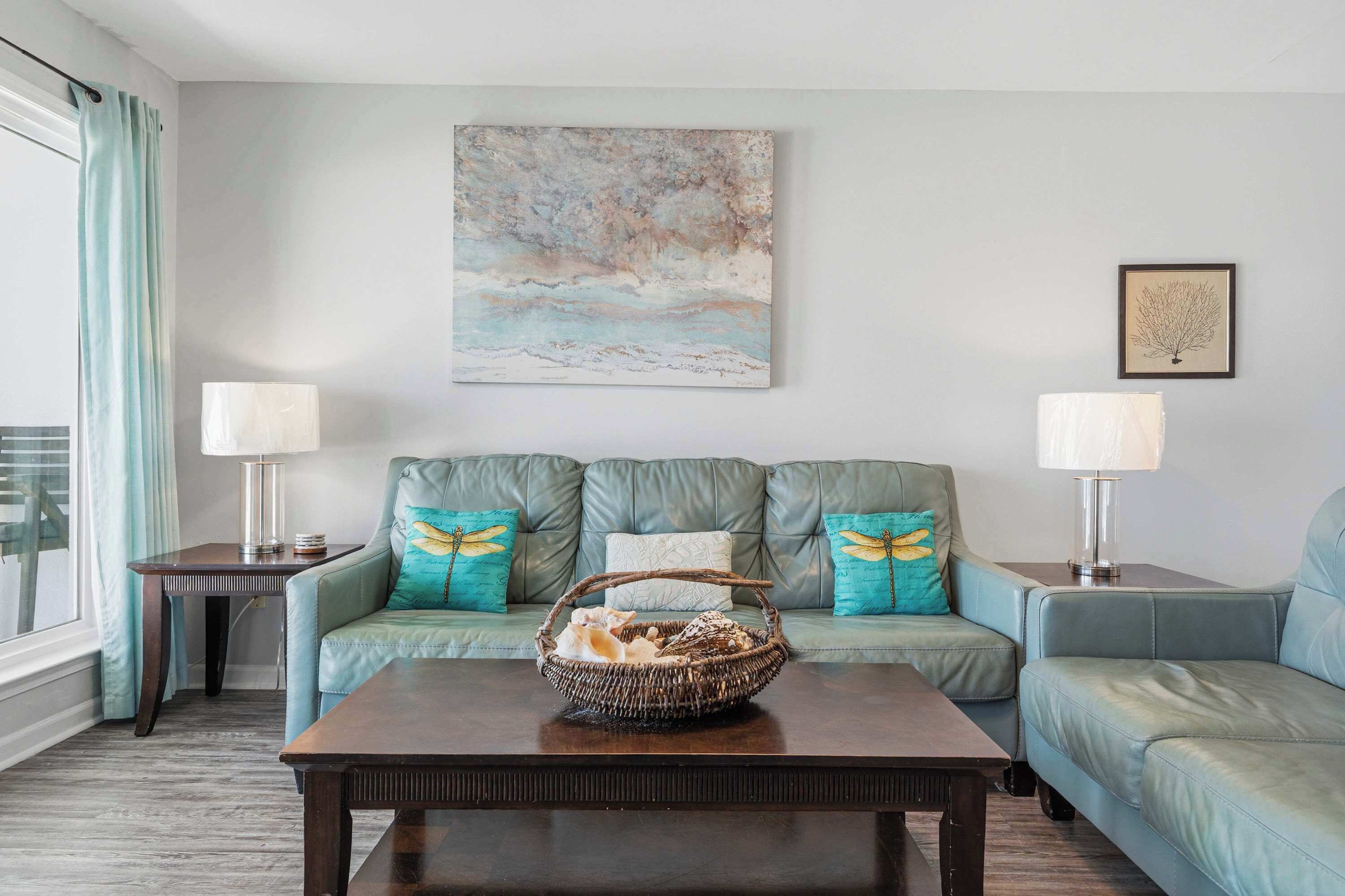 A living room with a sofa, two side tables, a coffee table, and a painting on the wall.