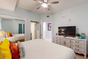 A bedroom with a bed, dresser, TV, and a ceiling fan. - Vibrant vacation home by the beach with pool, hot tub, & fitness facility (Panama City Beach)