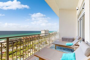 Ein Balkon mit Meerblick, eine Lounge mit Tisch und Stühlen sowie eine kleine Sitzecke mit Kissen.