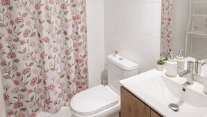 A modern bathroom with a toilet, sink, and shower curtain. - Central and modern apartment in Temuco.Cowork/gym/lavandería entrance by Safecard. (Cautin)