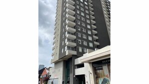 A high-rise building with multiple balconies and a storefront labeled "SALA DE". - Central and modern apartment in Temuco.Cowork/gym/lavandería entrance by Safecard. (Cautin)