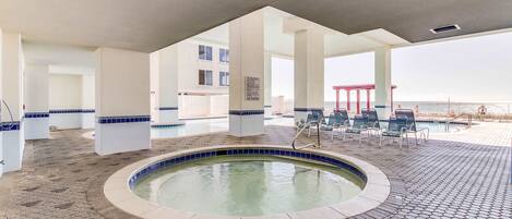 A pool area with a hot tub, lounge chairs, and a view of the sea.