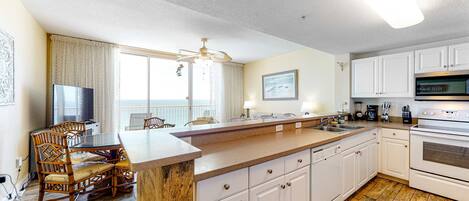 A kitchen with a wooden dining table, white cabinets, and a large island.