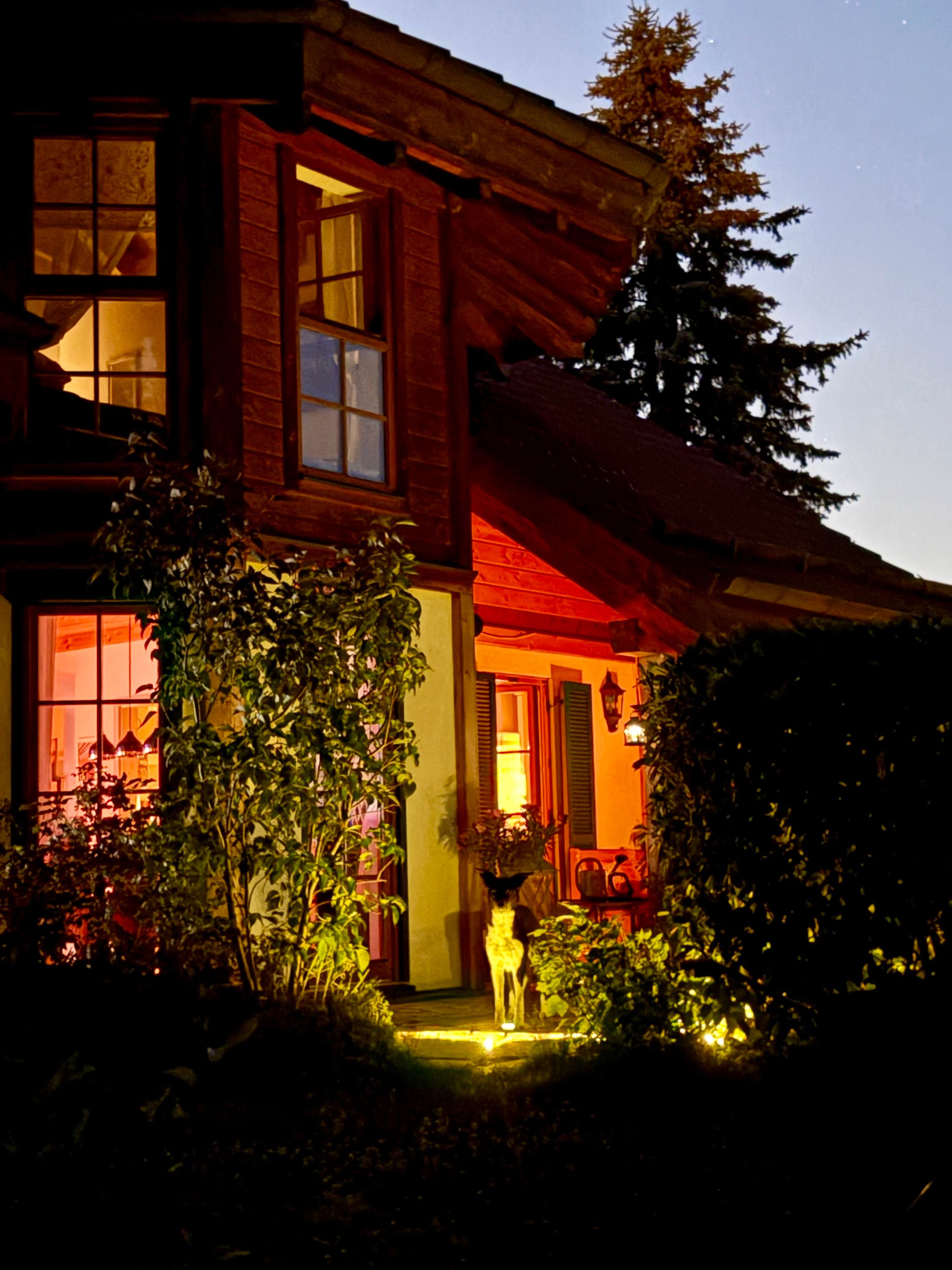 Ein Holzhaus mit Veranda, einem sichtbaren Fenster und einem Baum im Hintergrund.