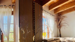 Un salon moderne avec un canapé en cuir aux lignes courbes, un mur décoratif orné de motifs verticaux, une plante en pot et un petit panneau indiquant le mot « chez soi » placé sur une petite étagère.