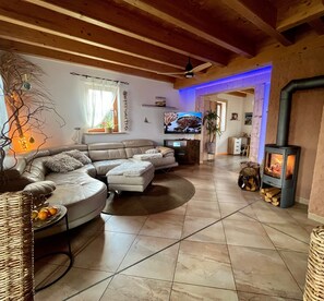 Un salon comprenant un canapé d’angle, un téléviseur à écran plat, une cheminée et un ventilateur de plafond.