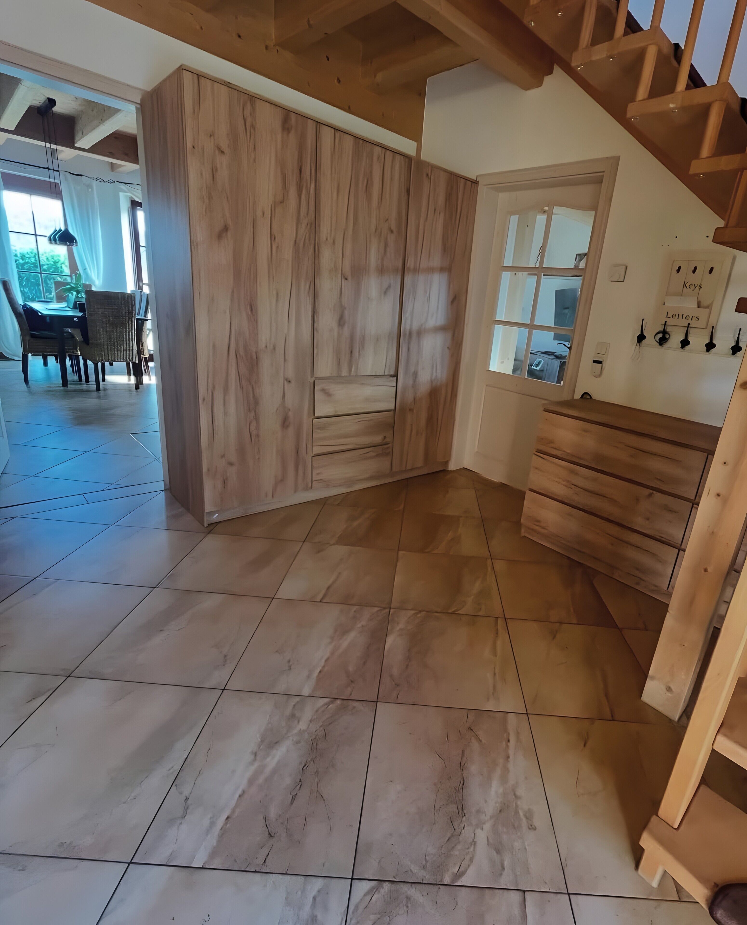 Una stanza con un'armadietto in legno, una zona pranzo con sedie e un tavolo, e una scala.