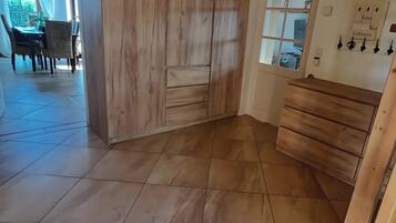 Una stanza con un'armadietto in legno, una zona pranzo con sedie e un tavolo, e una scala.