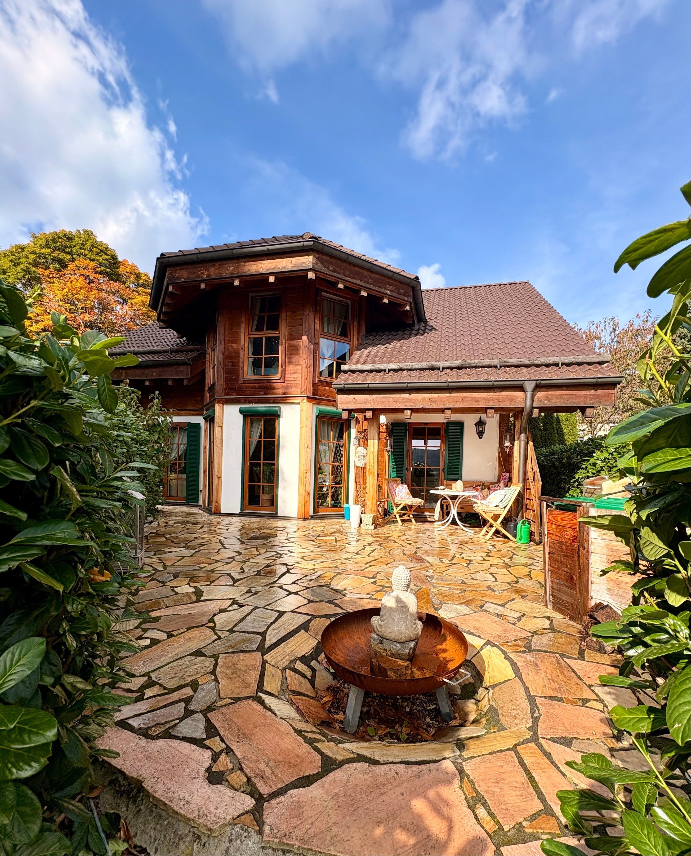 Una casa de madera con un patio de piedra y una fuente.