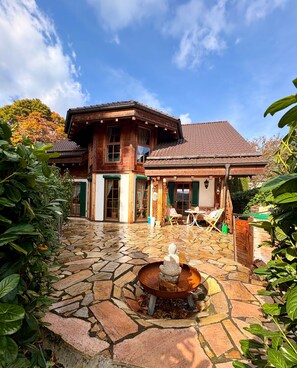 Une maison en bois avec un patio en pierre et une fontaine.