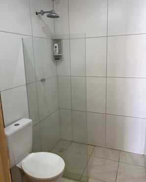 Ein kleines Badezimmer mit Fliesen, einer Toilette, einer Duschkabine und einer Glasabtrennung.