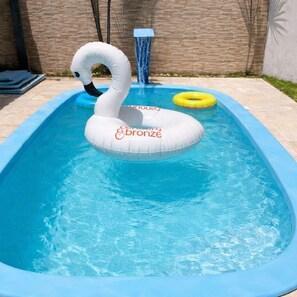 Una piscina con un flotador inflable con forma de cisne y un flotador circular amarillo.