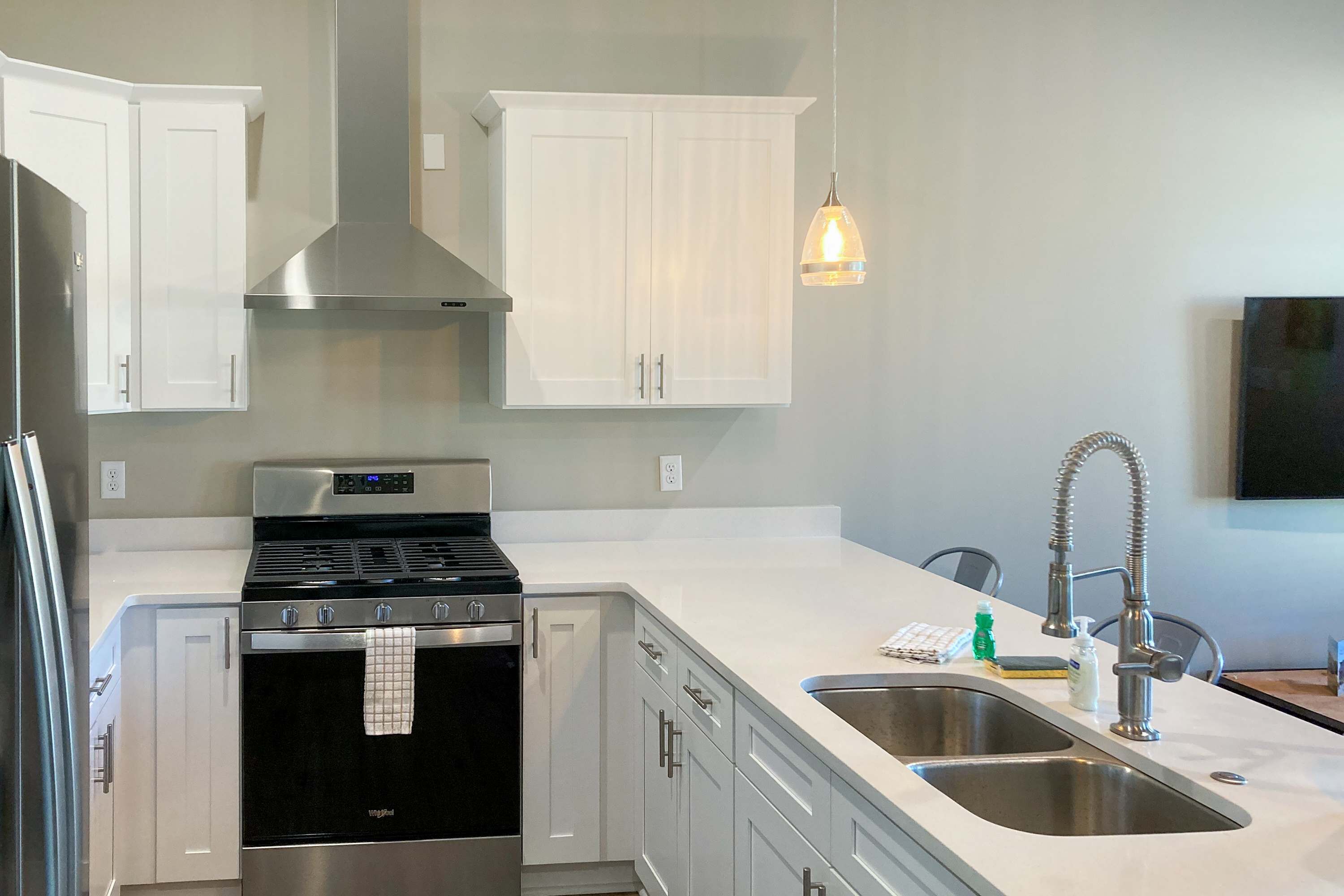 A modern kitchen with white cabinets, stainless steel appliances, and a double sink.