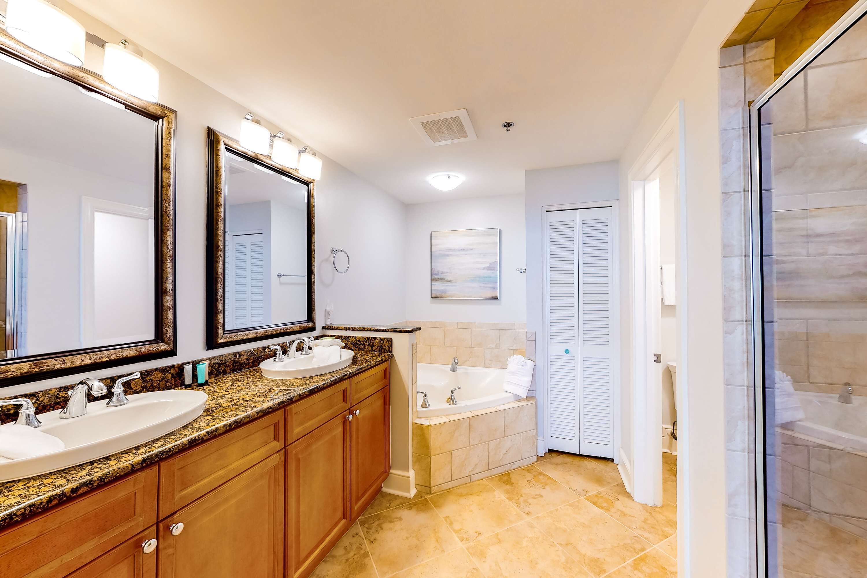A bathroom with two sinks, a bathtub, and a glass shower enclosure.