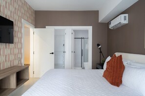 Een moderne hotelkamer met een bed, een televisie, een kledingkast en een airconditioner.