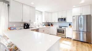 Een moderne keuken met witte kasten, roestvrijstalen apparatuur en een groot eiland.
