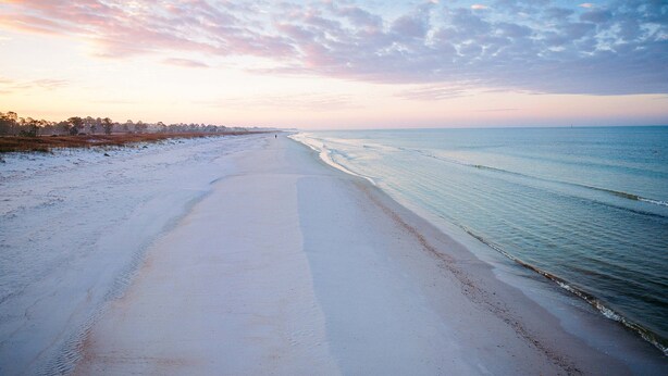 Ein Strand mit blauem Himmel und ruhiger See.