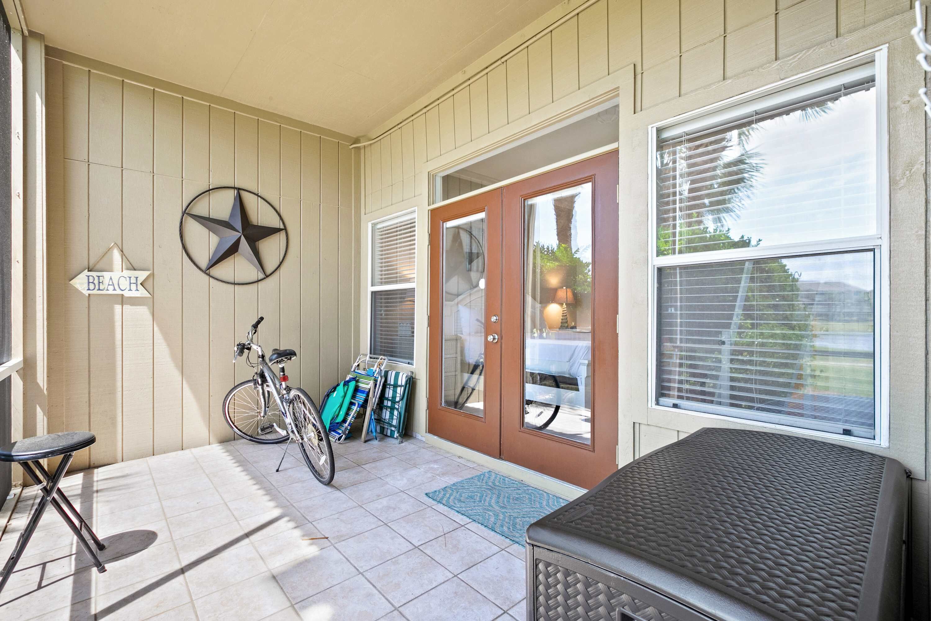 A covered porch with a bicycle, a star decoration, and a 'BEACH' sign.