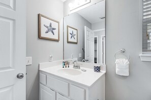 A bathroom with a white sink, a mirror, and framed starfish artwork on the wall. - Lovely condo with shared pool, washer&dryer, high-speed WiFi, and central AC (Navarre Beach)