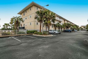 A multi-story hotel with a parking lot and palm trees. - Lovely condo with shared pool, washer&dryer, high-speed WiFi, and central AC (Navarre Beach)