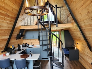 A modern loft-style interior with a kitchen, dining area, and a spiral staircase.