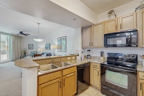 A modern kitchen with granite countertops, wooden cabinets, a built-in dishwasher, a double oven, and a microwave. - Coastal condo, shared pools, Onsite eateries, Spa, Wifi (Destin)