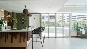 Een moderne receptie met een balie, barstoelen en een grote schuifglazen deur naar een buitenbalkon.