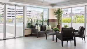 Een ruim balkon met een bank, stoelen en potplanten.