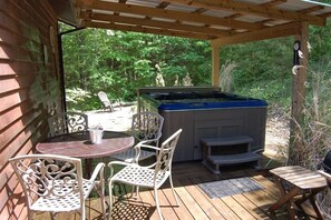 Eine Terrasse im Freien mit Whirlpool, weißen Metallstühlen und einer Holzterrasse.
