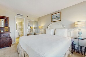 Quarto com cama grande, mesas de cabeceira, cômoda e espelho.
